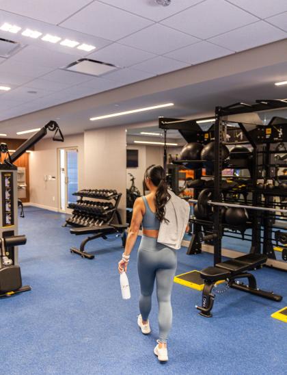 Woman wearing exercise gear walking through fitness center at LUMA Hotel SF